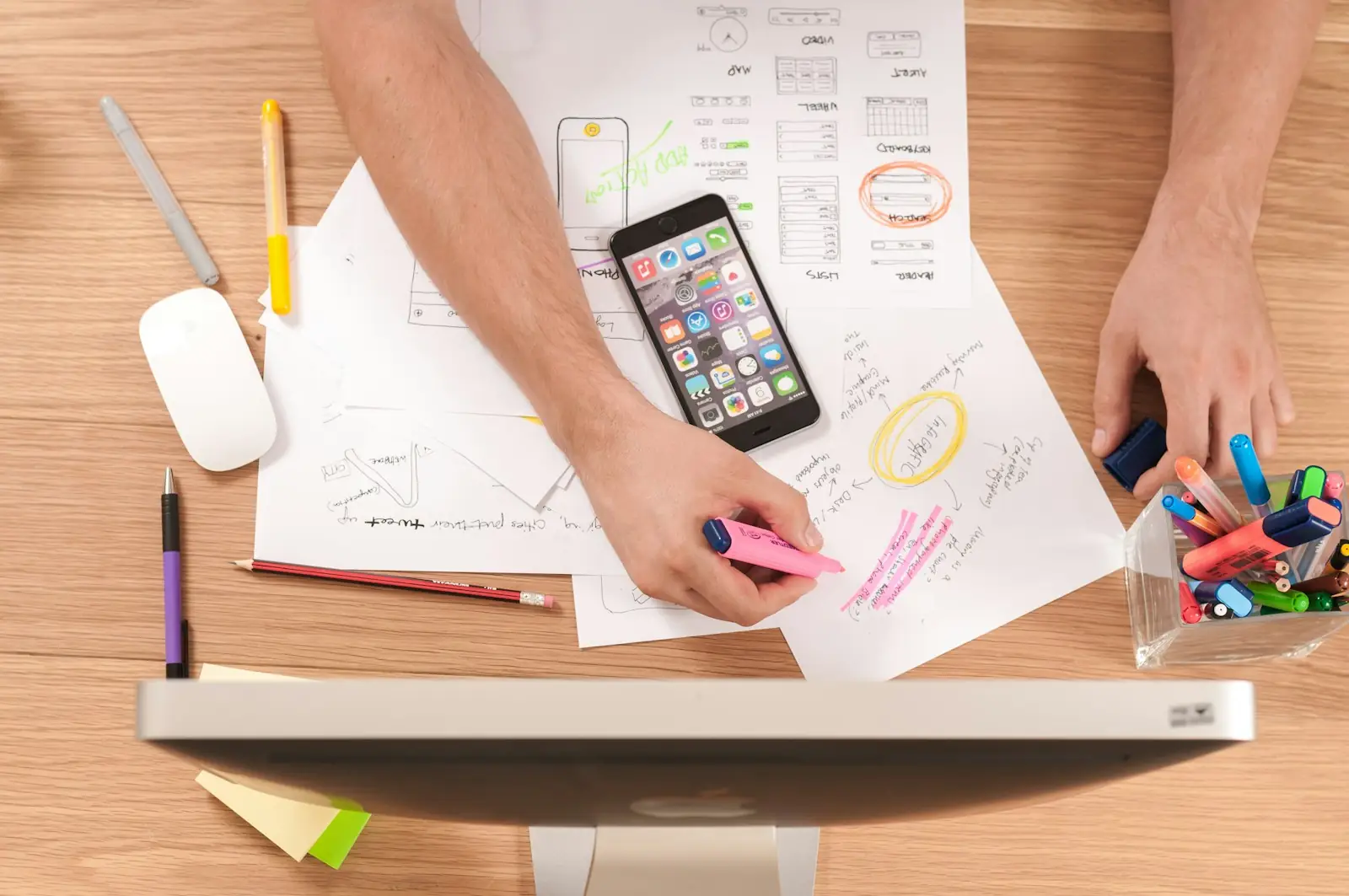 Hand-drawn website wireframes and a phone on a desk during page planning